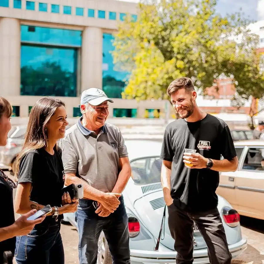 Equipe da Full Garage conversando com clientes ao lado de um Volkswagen Fusca em Brasília