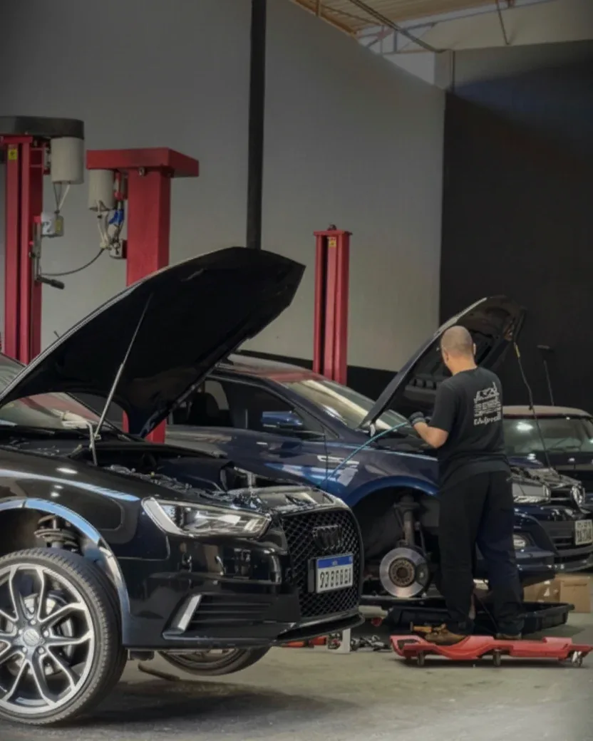 Interior da oficina Full Garage com veículos de capô aberto em revisão